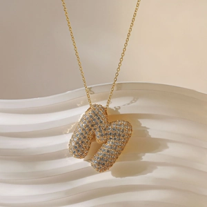 Detail van de gouden letter M hanger met fonkelende micropave kristallen aan ketting