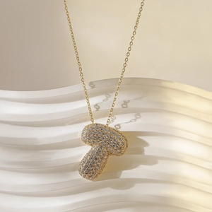 Detailopname van een gouden ketting met paddenstoel hanger en glanzende kristallen