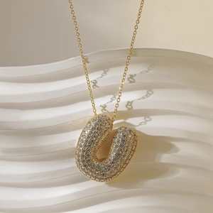 Detail van de 18k vergulde letter U hanger met glinsterende pavé gezette kristallen