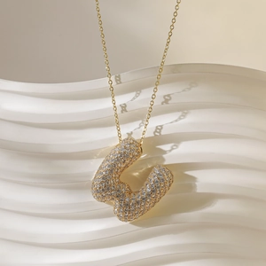 Macro-opname van vergulde letter U bubble hanger met sprankelende micro pave zirkoon