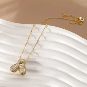 Macro-opname van gouden ketting met letter A hanger en zirkoon op een wit dienblad