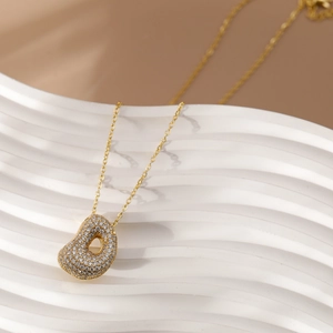 Detail van de hartvormige hanger met fonkelende zirkonia aan een minimalistische gouden ketting