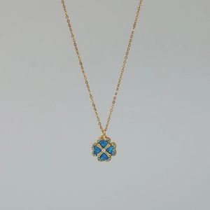 Detailopname van gouden klaverhanger met blauwe opaal en kristallen accenten