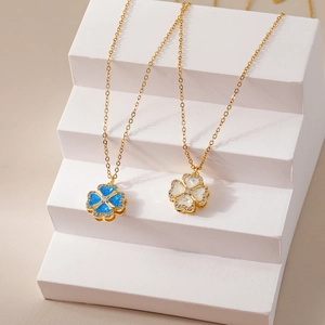 Gouden klaverkettingen met opaal en turquoise inleg op stenen trappen gepresenteerd