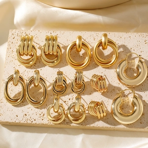 Collection of geometric 18K gold plated copper hoop earrings on a textured stone display