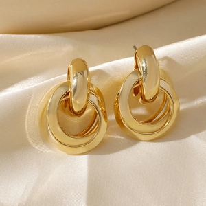 Detailed macro of 18K gold plated interlocking hoop earrings on beige silk fabric