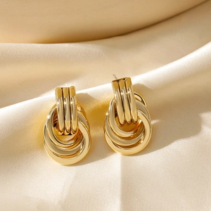 Close-up of 18K gold plated interlocking geometric hoop earrings on beige silk fabric