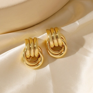Macro detail of 18K gold plated triple U-shape stud earrings on elegant silk fabric