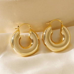 Detail of chunky gold hoop earrings with mirror-polished finish on silk fabric texture