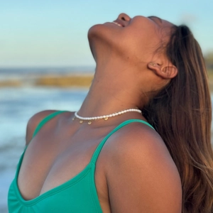 Bohemian choker necklace with white beads and gold disks worn on a beach background