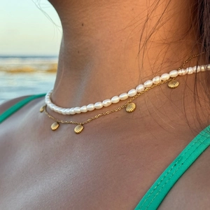 Close-up of bohemian double-layer necklace with white pearls and gold seashell pendants