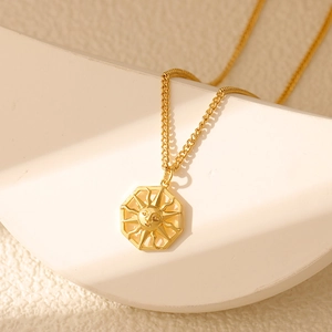 Close-up of vintage sun face pendant necklace with gold plating and octagonal frame