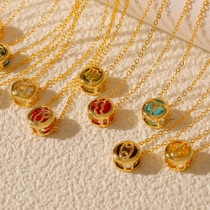 Close-up of gold zodiac necklace pendants with colorful zircon stones and engraved symbols