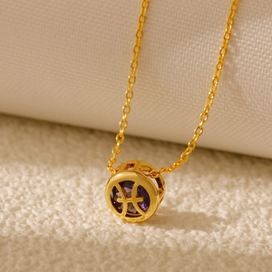 Close-up of gold Pisces zodiac necklace with hollow design and purple gemstone