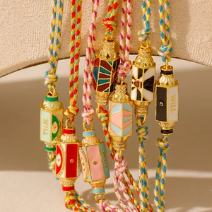Détail de bracelets tressés colorés avec pendentifs en émail hexagonal et accents dorés