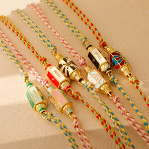 Détail de bracelets colorés tissés main avec perle en émail doré et zircons incrustés