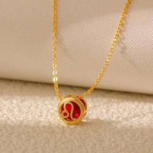 Close-up of golden Leo zodiac necklace with red zircon stone on white textured fabric