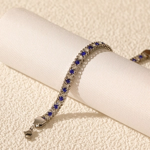 Detailed macro view of silver tennis bracelet with alternating blue and white zircon stones