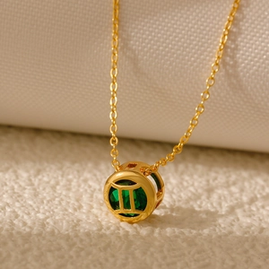 Detailed close-up of Gemini zodiac necklace with green gemstone and gold hollow pendant