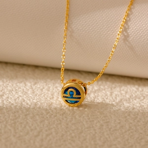 Macro shot of gold Libra zodiac pendant with blue zircon and hollow carved detail