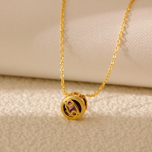Detail of gold Cancer zodiac necklace featuring a purple zircon and hollowed design