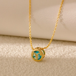 Detail of gold Aries zodiac pendant with light blue zircon and intricate hollow design