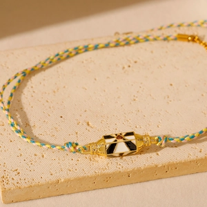 Gros plan d'un collier en cordon tissé avec un pendentif en émail doré style tarot