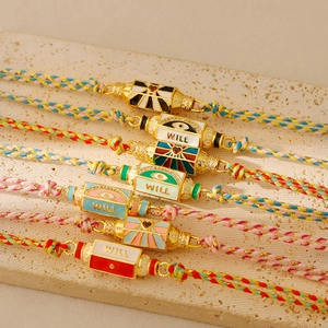 Détail de bracelets tressés avec cordons colorés et pendentifs en émail doré style tarot