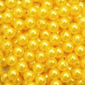 Macro detail of bright yellow acrylic round beads with glossy pearl finish for DIY jewelry