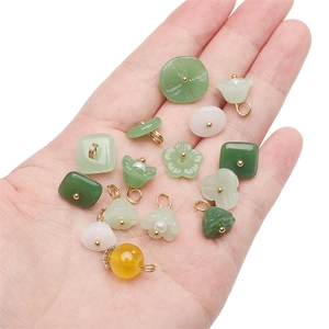 Hand holding assorted glass faux jade pendants and beads for DIY jewelry making