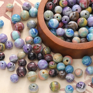 Gros plan de perles en résine colorées à texture marbrée pour bijoux DIY dans un bol en bois
