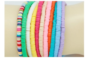 Gros plan de dix bracelets colorés en perles Heishi de 6 mm superposés sur un poignet