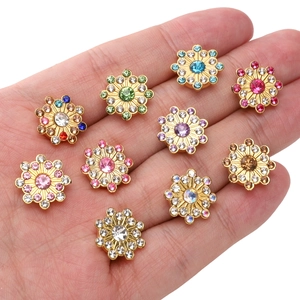 Detalle macro de botones de flores de diamantes de imitación multicolores en una mano para escala