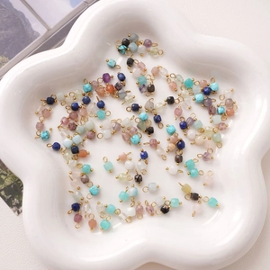Macro shot of colorful faceted natural stone pendants with gold loops in a ceramic tray