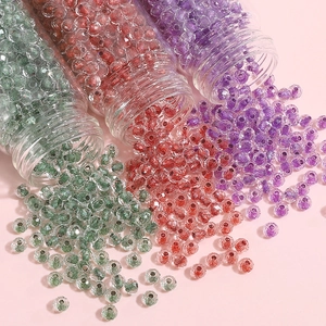 Macro detail of 4mm green and pink faceted glass beads spilling from glass jars for DIY