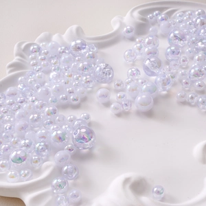 Détail macro de perles rondes en acrylique translucide irisé sur un plateau vintage blanc