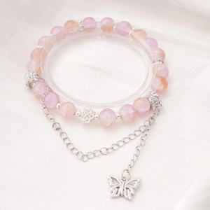 Detailansicht eines Perlenarmbands mit rosa Perlen und silbernem Schmetterling