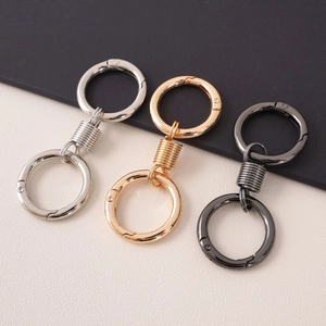 Detailed view of metal spring keyrings in silver, gold, and gunmetal finishes on textured surface