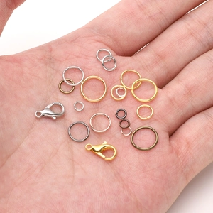 Macro shot of various metal jump rings and lobster clasps held in palm for DIY jewelry making