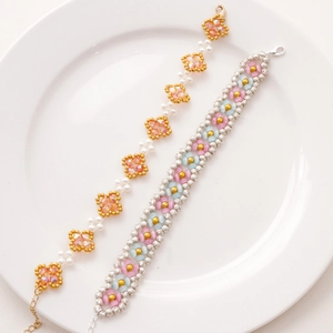 Macro shot of two handmade floral beaded bracelets with metal lobster clasps on a white tray
