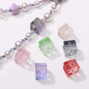 Close-up of 11mm colorful glass cube beads with embossed sun patterns for DIY jewelry