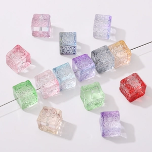 Macro shot of 11mm glass cube beads with floral relief and transparent rainbow colors