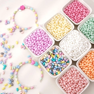 Detail of colorful oval macaron glass beads for DIY necklaces with floral heart charms