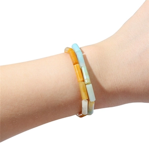 Vue macro de perles cylindriques orange et turquoise sur des bracelets élastiques