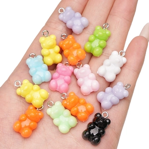 Colorful 11x21mm acrylic bear charms for DIY jewelry making held in palm against white background