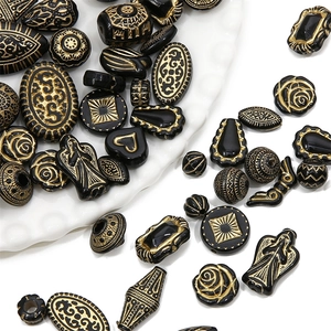 Flache Ansicht von Vintage Acrylperlen in Schwarz und Gold mit Herz- und Engelrelief