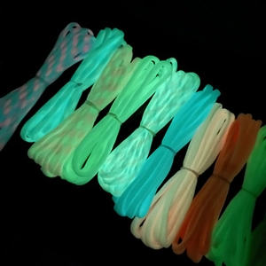 Luminous 4mm nylon paracord in multiple neon colors glowing on a dark background