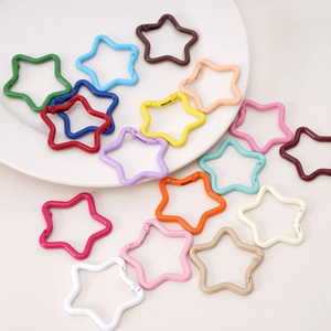 Macro shot of colorful star-shaped alloy keychains and DIY craft accessories on a white plate