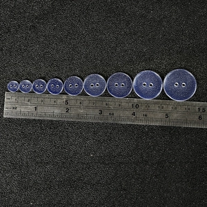 Nine translucent light blue resin buttons in sizes 10mm to 25mm with two holes