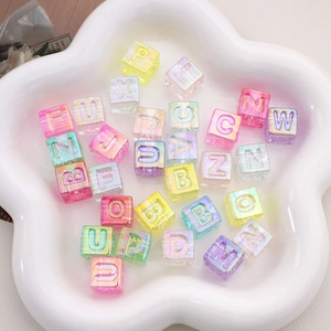 Vue macro de perles cubes alphabet en acrylique translucide de 12mm pour création de bijoux